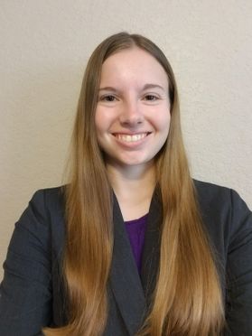 Photo of smiling young woman with long hair, dark jacket, purple shirt