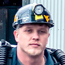 Josh Riffle is shown wearing a hard hat with a Flying WV on the front.