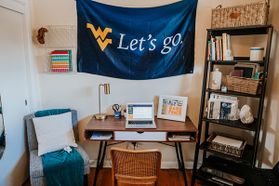 makeshift home office with WVU banner above computer desk