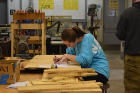 WVU sculpture student traces stencil onto wood during class
