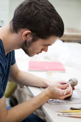 In WVU ceramics studio, a student creates a like-life figurine.
