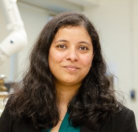 Headshot of WVU faculty Oishi Sanyal. She is pictured inside of her lab wearing a black jacket over a green blouse. She has long, dark, wavy hair. 