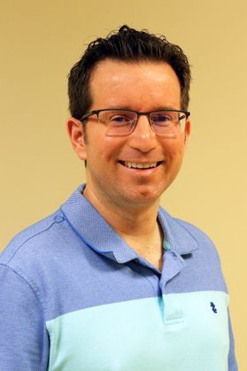 photo of smiling man with glasses, two-colored polo shirt 