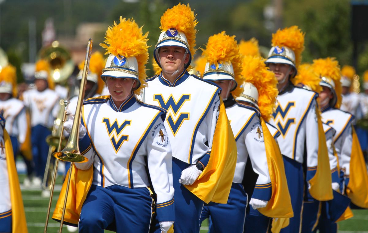 WV marching band marches in a line with their instruments in their right hands.