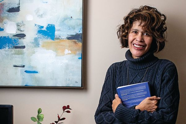 smiling woman holds book standing beside art