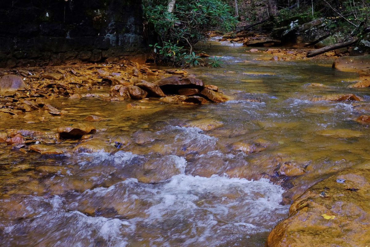 flowing stream with orange-ish residue on the banks