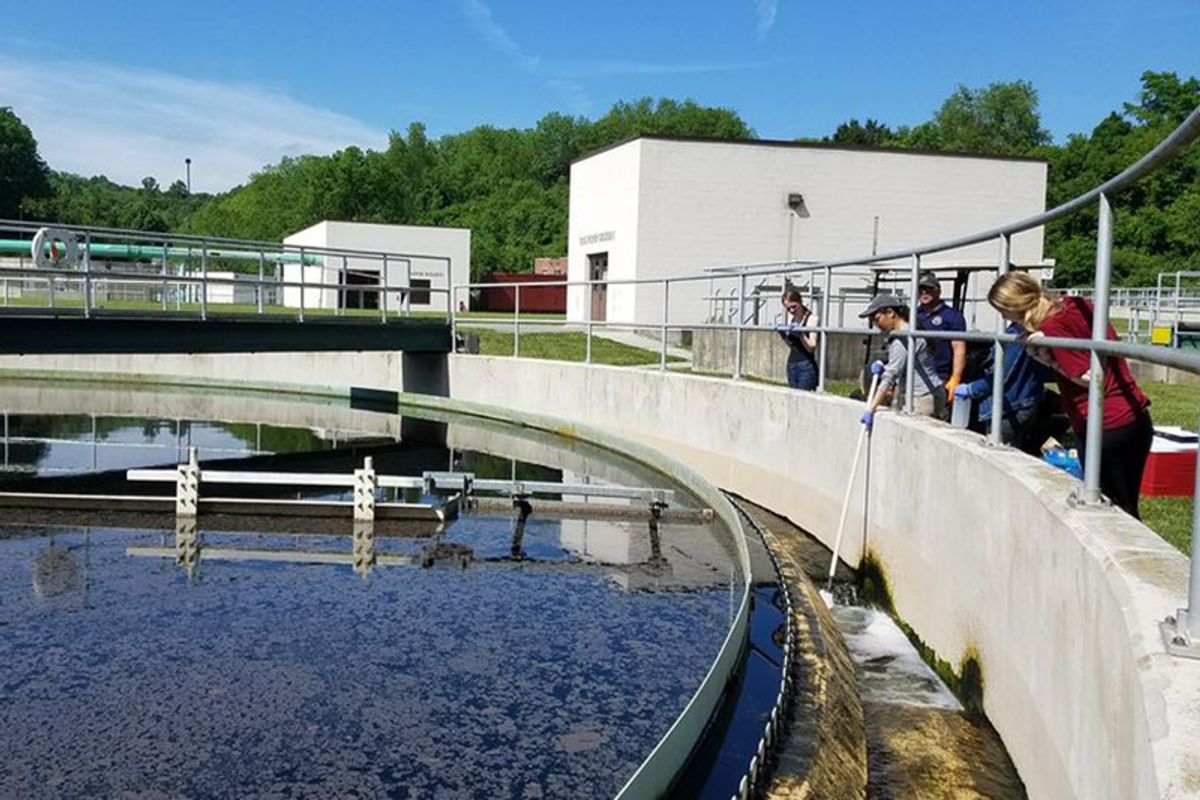 A photo showing people looking at a holding tank in a wastewater facility.