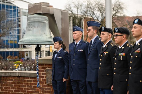 Six WVU ROTC students stand at attention to the right of a bell from the USS West Virginia in the Oglebay Plaza on the University's Downtown Campus during a Pearl Harbor Day ceremony. The Mountainlair can be seen in the background of the photograph. 