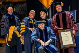 Donald Hoylman receives an HDR from WVU President Gordon Gee (R) and Dean Javier Reyes (L) at the 2018 December Commencement.