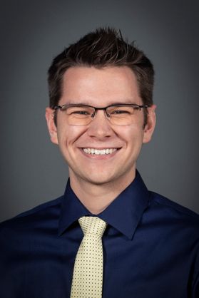 smiling young man wearing glasses, shirt and tie