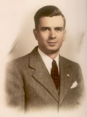 A sepia-toned photo of a man in a gray suit and dark tie with his dark hair slicked back