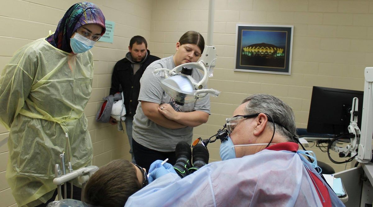 Child receives dental care while parents and dental student observe