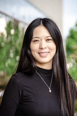 woman with black hair in a black shirt poses outside for a photo