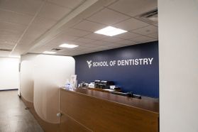 Reception desk with school of dentistry on the wall behind it.