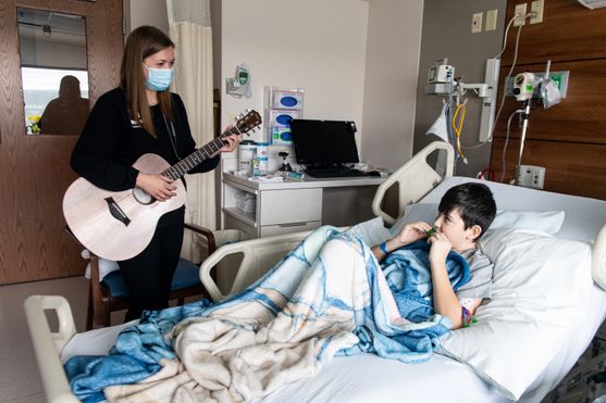 Music therapist Hannah Bush plays guitar while pediatric patient Christian Martin plays a harmonica