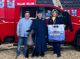The Demniak family poses with their award winning lamb in front of a red truck. 