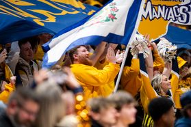 bearded man cheering in crowd beneath WV state flag