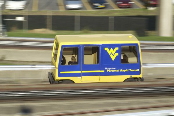 Shot of a blue and gold WV personal transit going by on the tracks. 