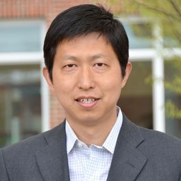 Headshot of WVU professor Yu Gu. He is pictured outside with a blurred building in the background. He is an Asian man and is wearing a gray jacket with a white dress shirt. He has short black hair.