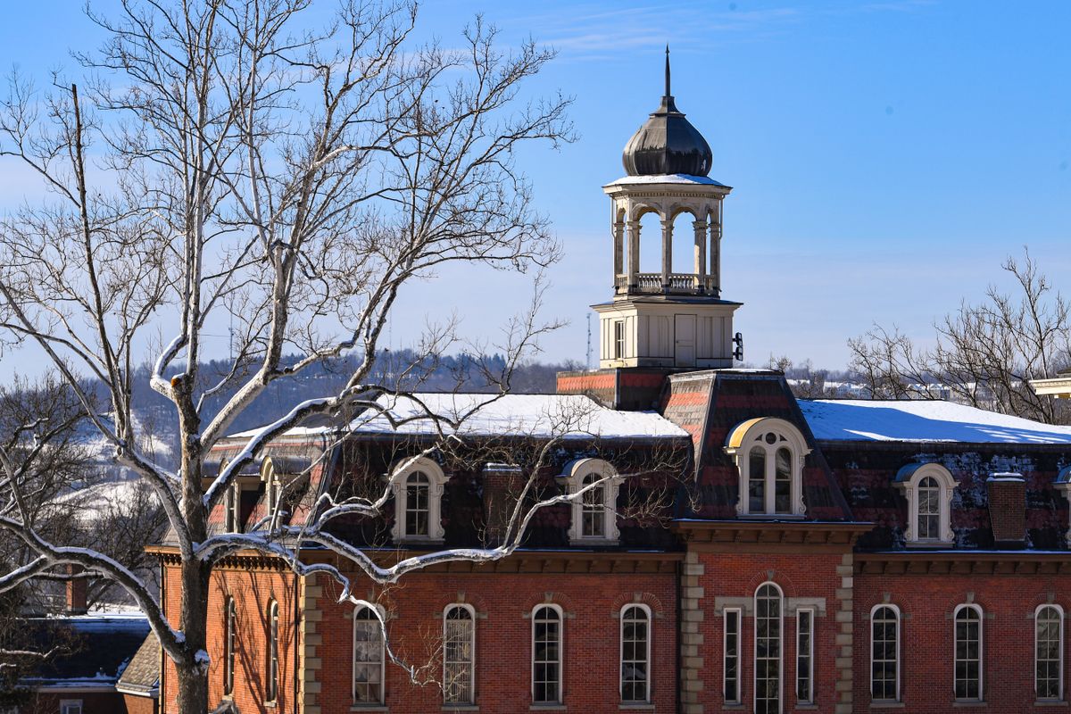 large brick building with cupola, snow on the roof
