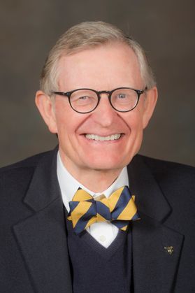 This is a portrait of Gordon Gee who is wearing a navy blue jacket, blue vest and gold and blue bowtie.