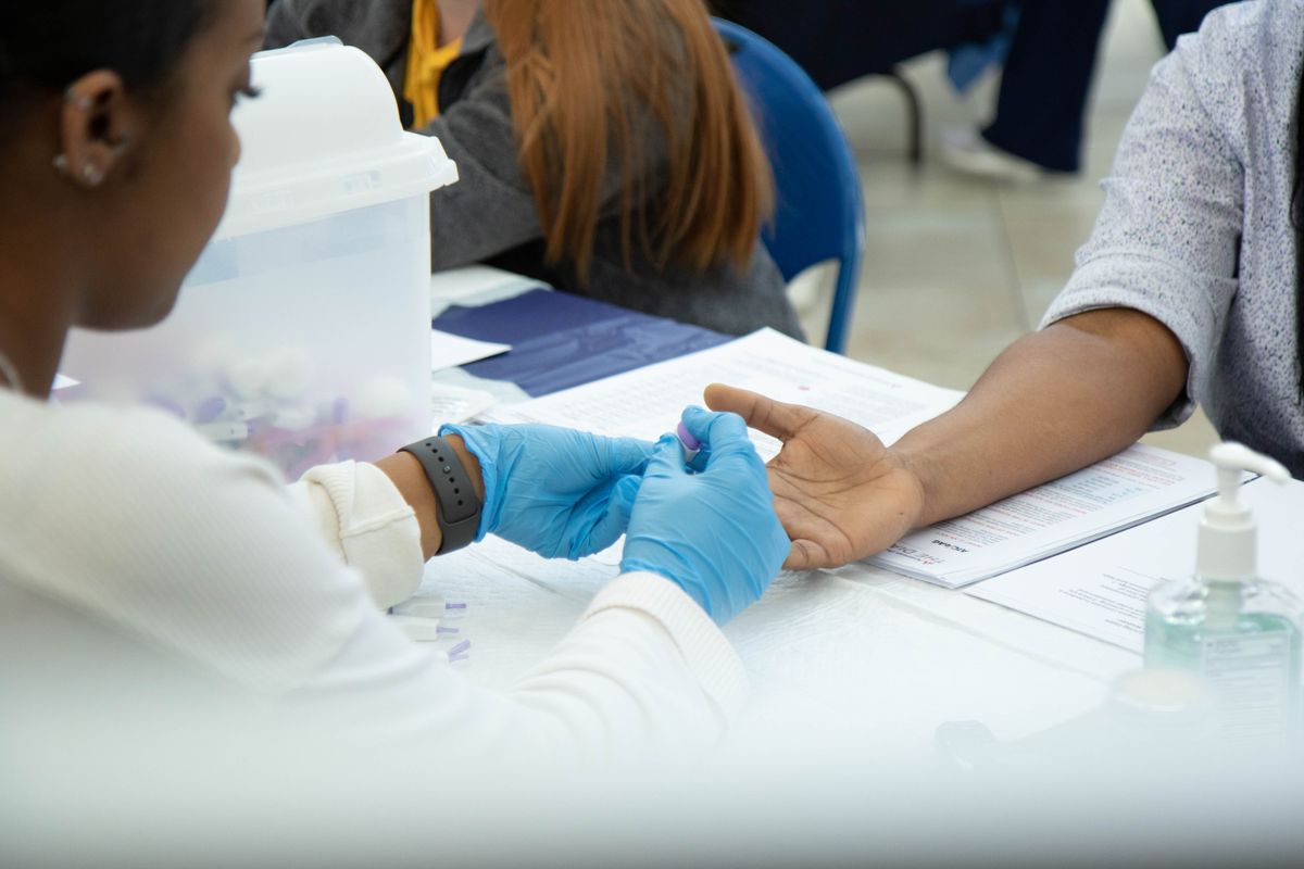 woman in lab coat and blue gloves holds a hand, palm up