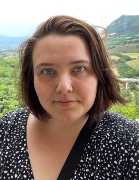 Headshot of WVU student Virginia Affemann. She is pictured outside wearing a black polka-dotted blouse. She has short brown hair. 
