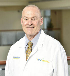 Dr. Clay Marsh wearing a WVU Medicine white coat with a dark gold tie and grey button up dress shirt.