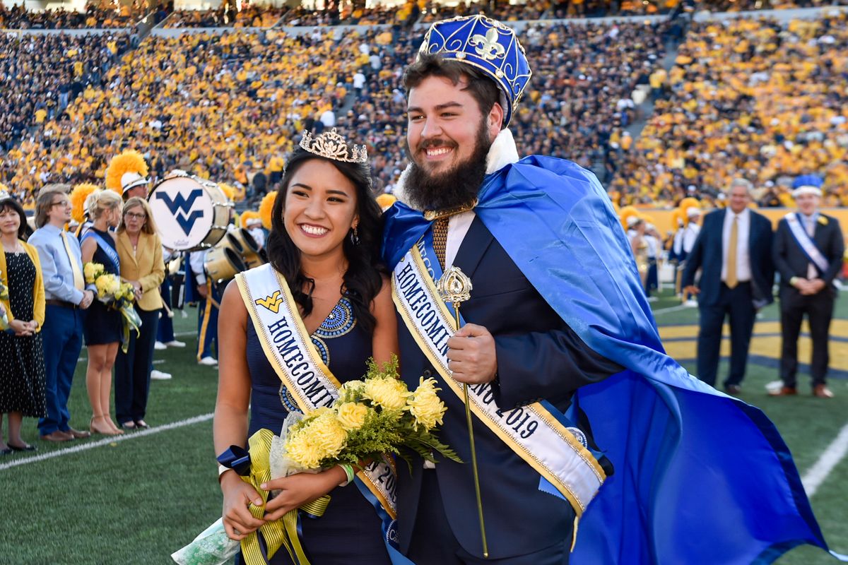 young woman and young man in homecoming crowns, capes, regalia