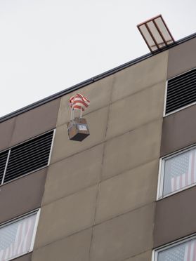 A box on a parachute floats from a building