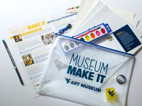 A WVU branded bag stating, "Museum Make It." Next to the bag is plain sheets of paper, a painting kit, and informational papers.