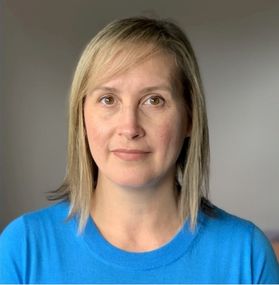 Headshot of WVU Extension professor Kerry Gabbert. She is standing in front of a gray wall wearing a bright blue shirt. She has shoulder length blonde hair. 