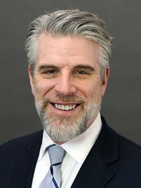 photo of bearded man with gray hair in suit and tie