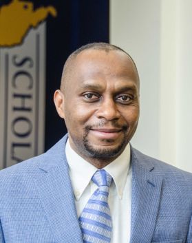 Headshot of WVU professor Donald Adjeroh. His is pictured inside wearing a light blue suit over a white dress shirt and a light blue and white striped tie. He has short black hair and a black goatee. 
