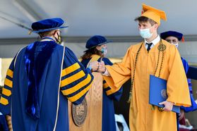 men in graduation regalia greet each other