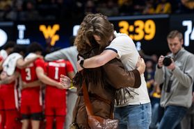 Braden Adkins hugs Mikel Hager on the floor of the Coliseum after being named the new Mountaineer mascot.
