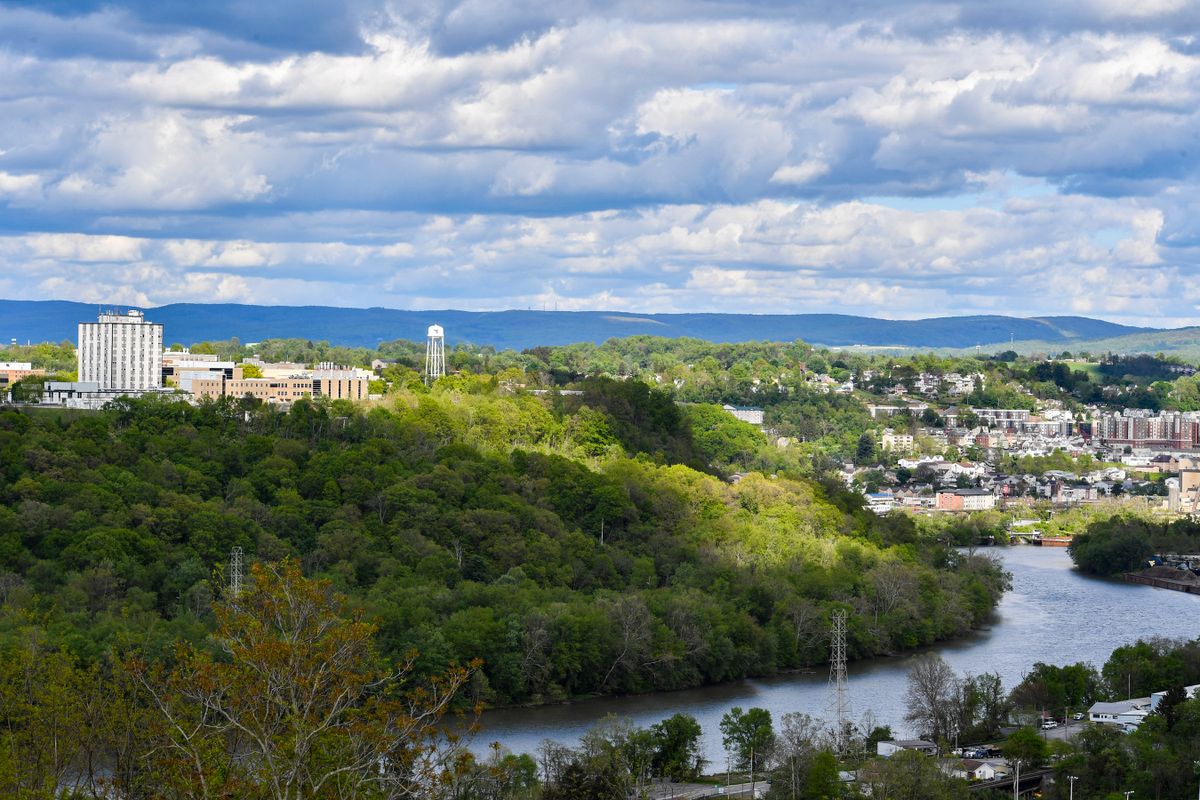 A wide shot of Morgantown with both the Evansdale and Downtown campus visible, along with the river, under blue skies with clouds