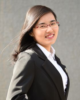 Portrait of Yuhe Tian, she has straight brown hair and is smiling. She is wearing glasses and a suit. 