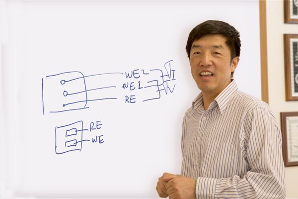 WVU researcher Xingbo Liu standing in front of a white board with equations on it.