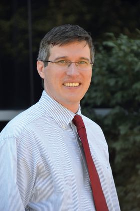Smiling man in red shirt and red tie wearing glasses