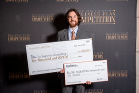 young man with beard and longer hair holds two checks