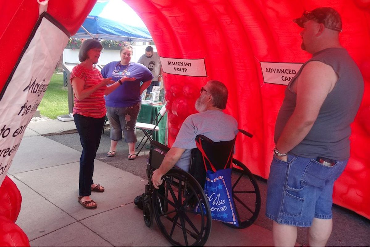 man in wheelchair speaks with woman holding clipboard, man in foreground
