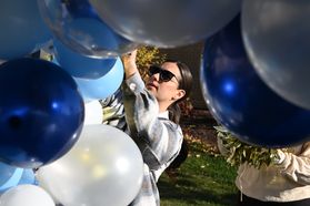 Blue and white balloons surround a person.