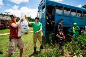 Young people unload items form a bus