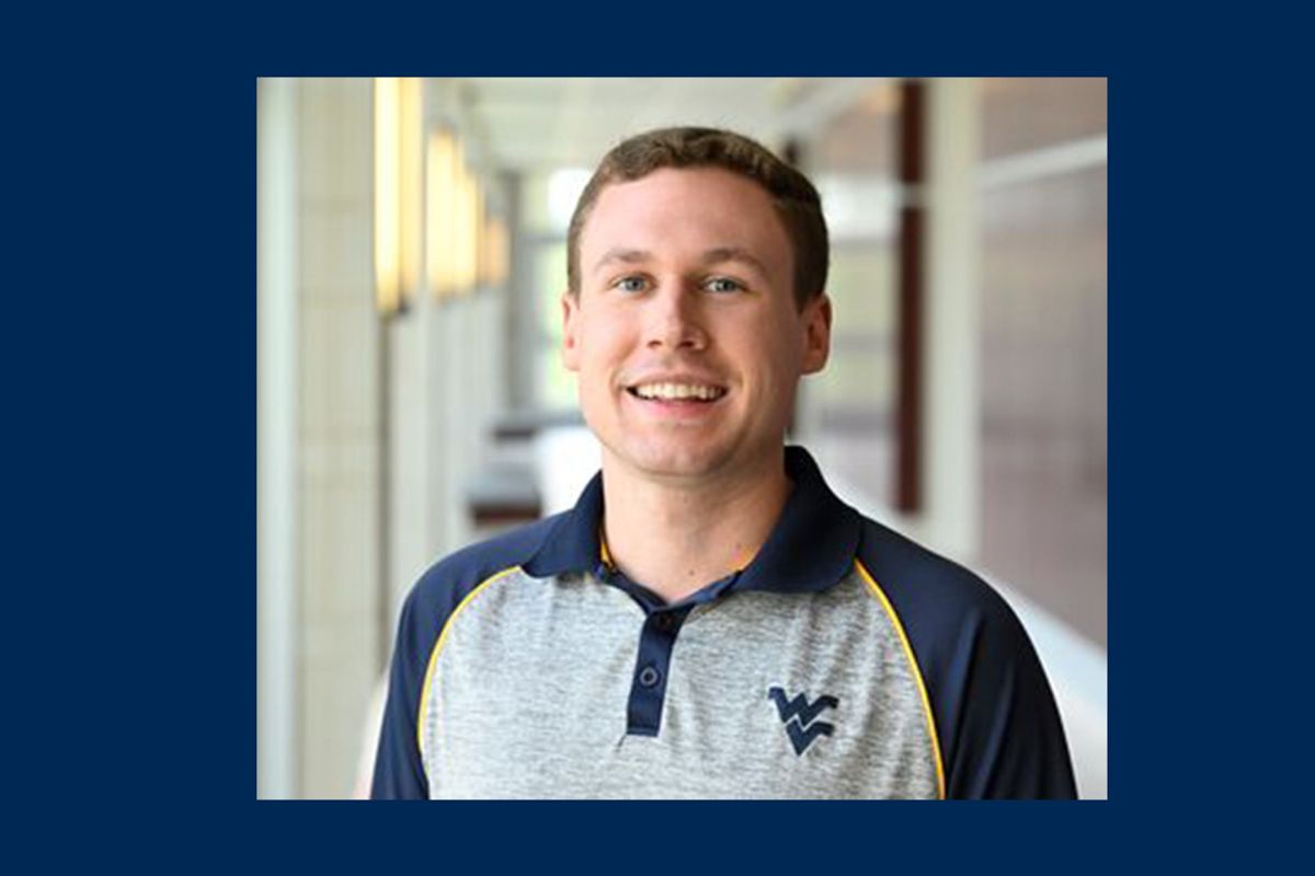 Photograph of WVU law student Parker D’Antoni pictured inside. He is wearing a navy blue and gray, WVU-branded golf shirt and has short, light brown hair. 