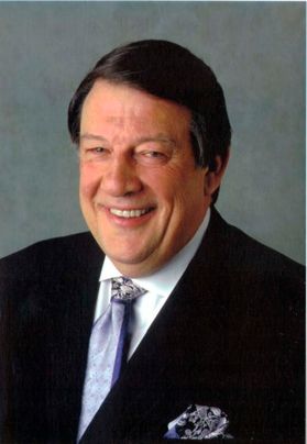 smiling man with dark hair wearing a suit