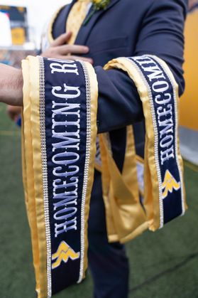 Picture of the sashes given to WVU Homecoming Royalty. They are blue and gold with the word Homecoming and the flying WV embroidered on them in white and gold. 