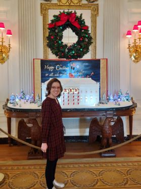A photograph of WVU employee Mary Veselicky posing in front of a holiday display in the White House. 