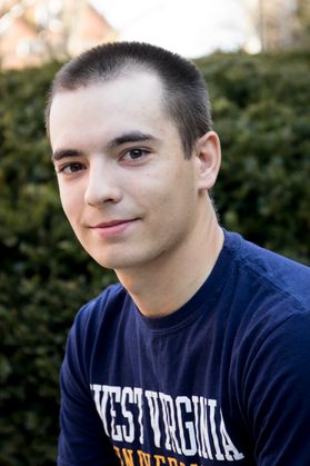 photo of a young man with dark hair wearing a West Virginia University shirt