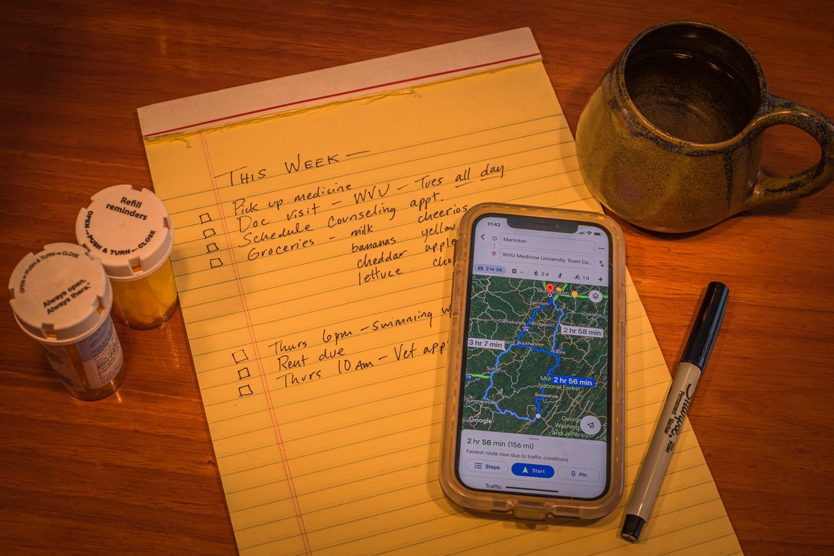 notepad with cellphone map, pen, pill bottles, mug